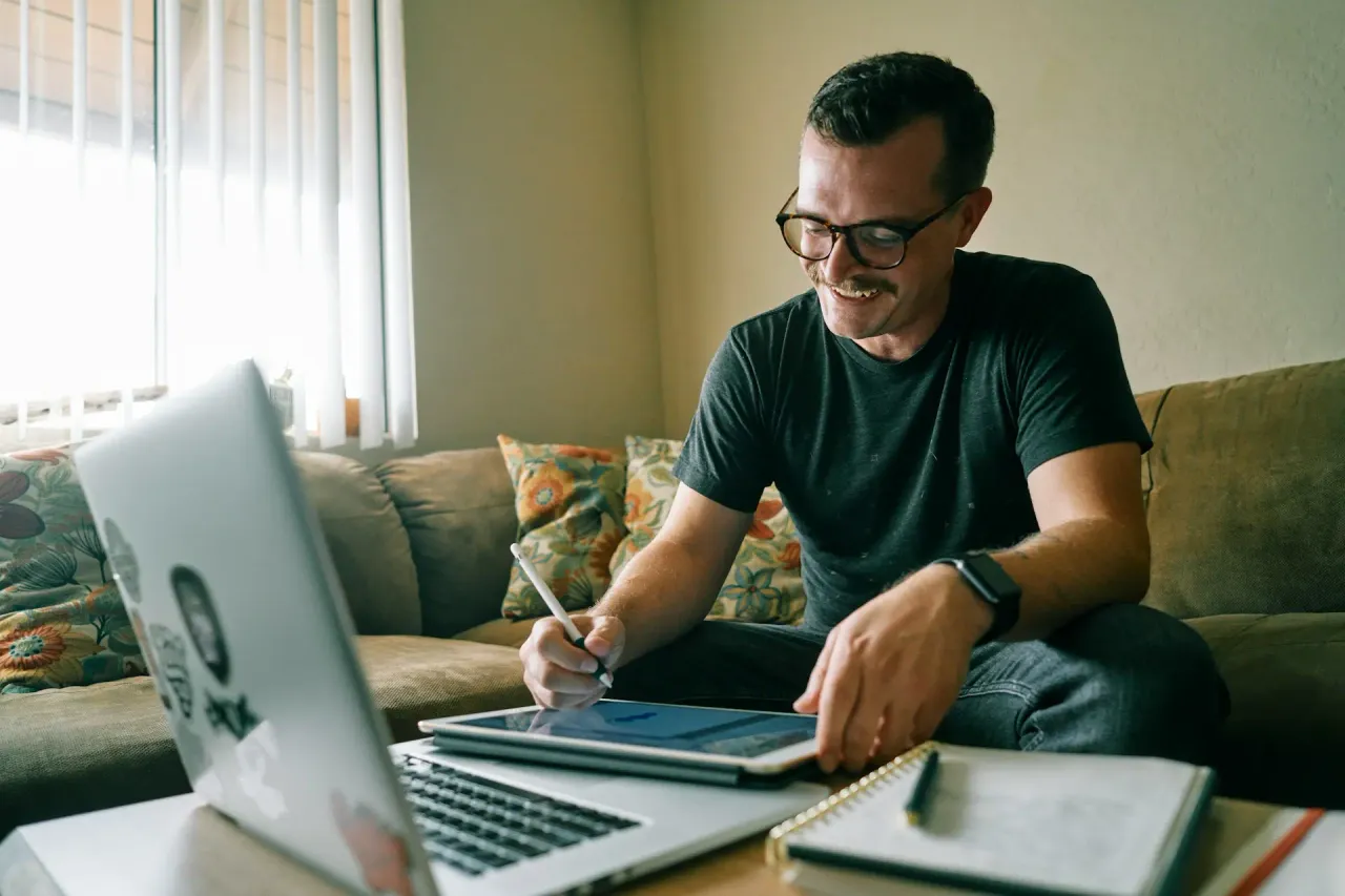 A couple at home, smiling at a laptop during an online conversation.